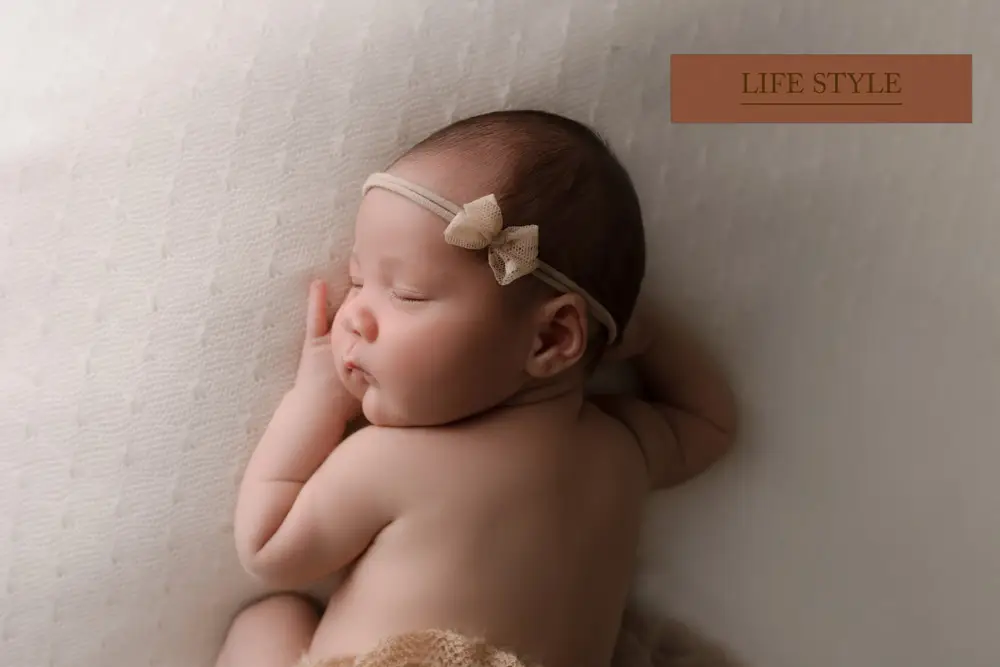 photographie d'un bébé dormant sur le ventre les mains sous son visage
